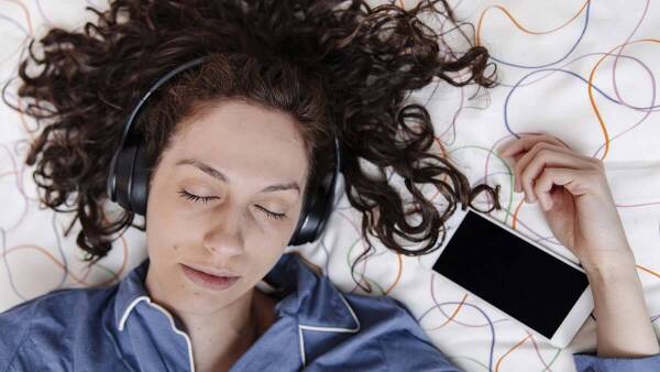 Woman listening to music with closed eyes on bed